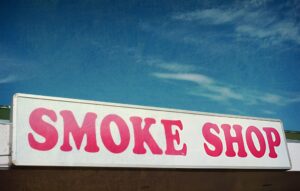 Smoke shop near me—storefront sign with bold pink letters above entrance.
