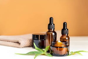 Buy CBD Oil Port St. Lucie Florida amber dropper bottles and jars with hemp leaves on white surface.