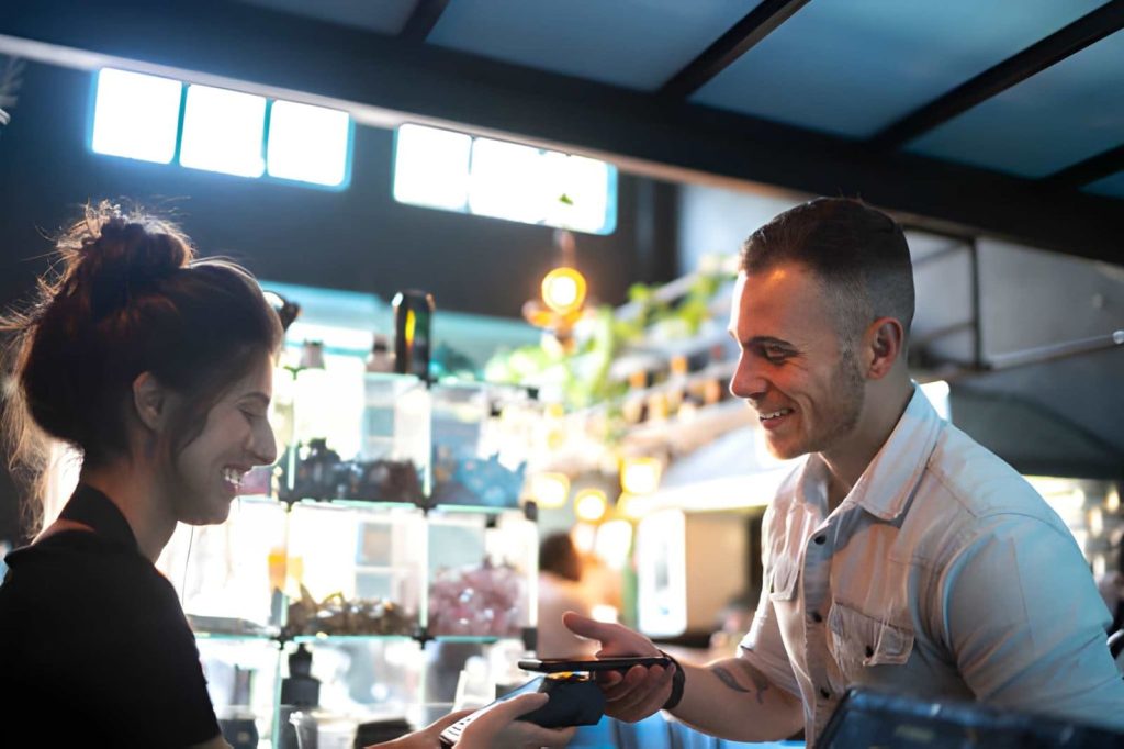 Dispensary Port St Lucie customer using a smartphone for contactless payment at a modern retail checkout counter.