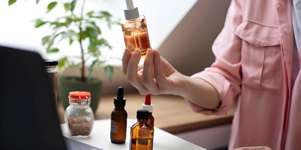Buy CBD Oil Port St. Lucie Florida person holding dropper bottle with golden liquid near workspace.