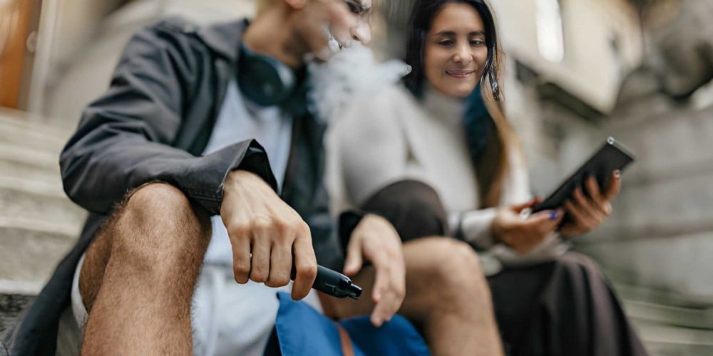 Disposable vapes in Treasure Coast person using vape outdoors on stone steps.